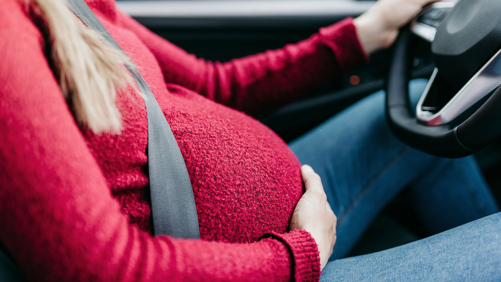 Pregnant woman sitting in the drivers seat of a car